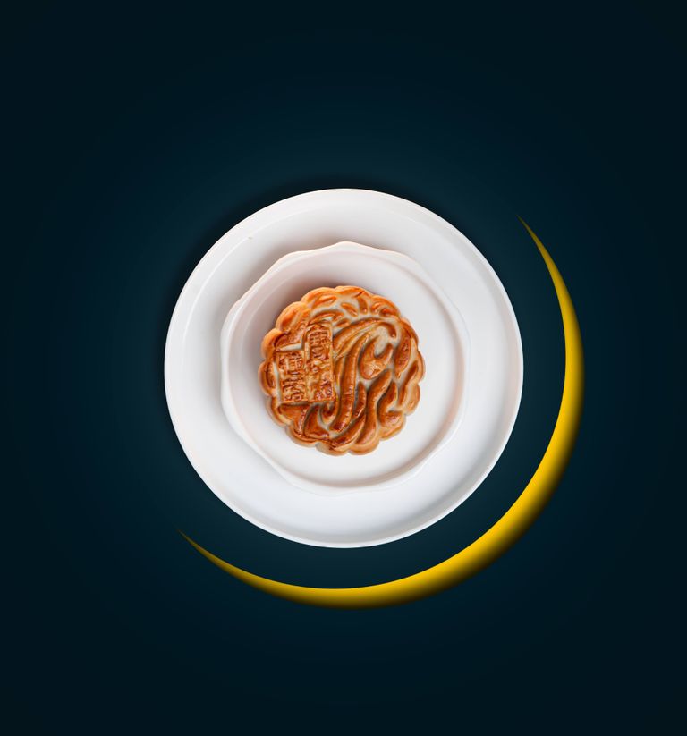 Top view of a mooncake on a plate with a crescent design, symbolizing Mid-Autumn festival.